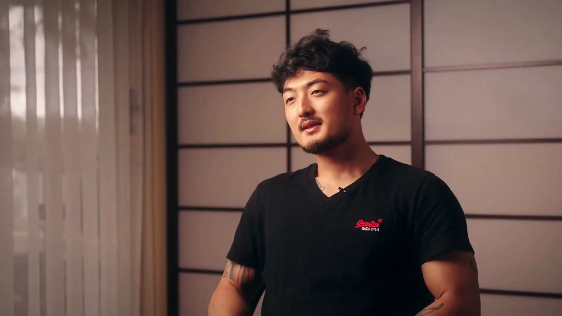 Harrison Saito speaking to camera in a room with shoji screens