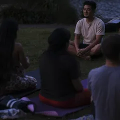Harrison seated in a circle of people by the water