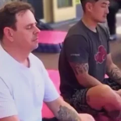 Harrison and a client sitting cross-legged on the mats, eyes closed