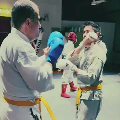 Two karateka in gi and gloves sparring in the dojo
