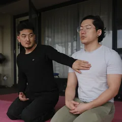 Harrison kneeling beside a client, a hand on his chest, the client’s eyes closed