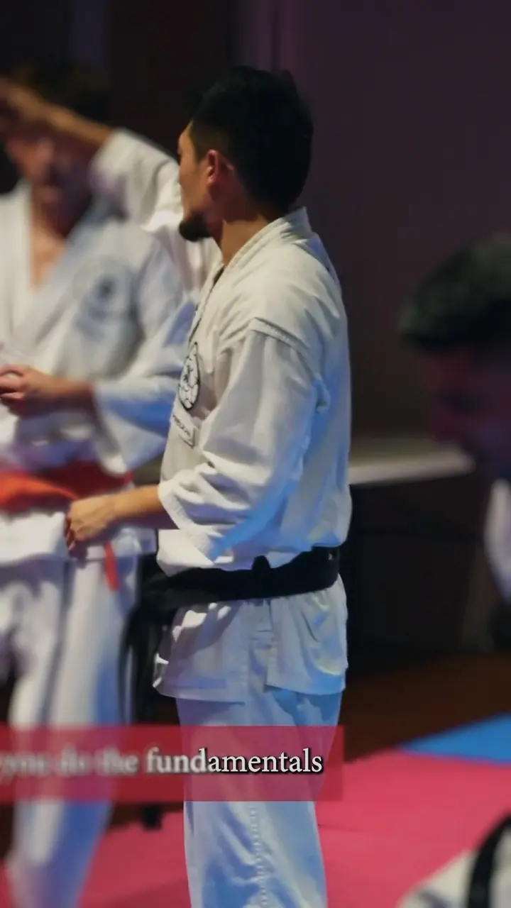 Harrison in his gi and black belt, teaching technique in the dojo