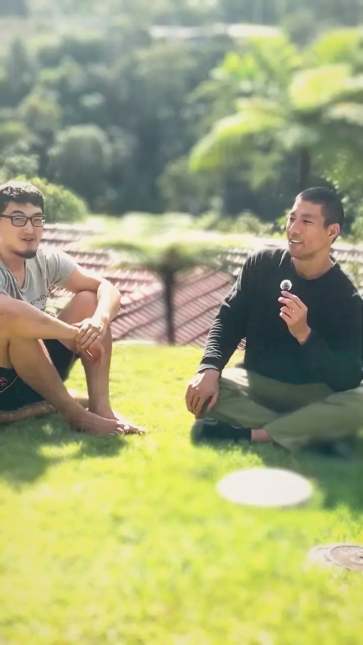 Harrison and a friend sitting on the lawn, mid-conversation