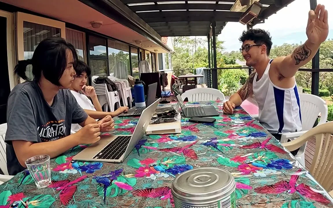 Harrison Saito teaching two students at a table with laptops